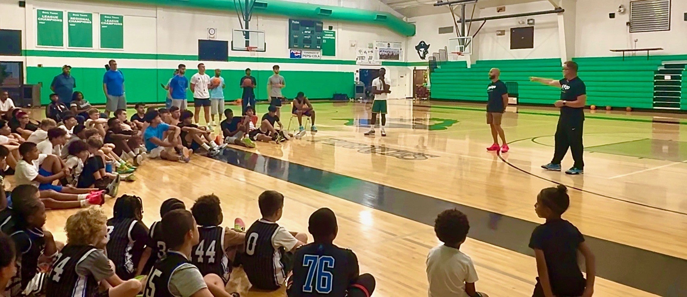 Rob (CEO) and Zach teaching a hydration course to PLUTO basketball team in a school gym.